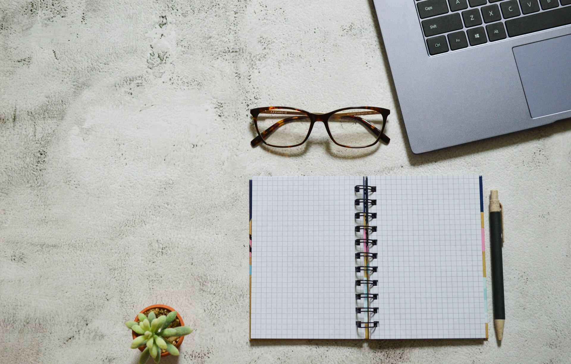 Eyeglasses resting on a notebook beside work notes